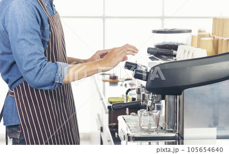 Close up hands coffee barista man make hot cup espresso shot from coffee machine. Cappuccino with milk in italian coffee shop cafe. Close up hands of barista use machine make black drinking hot cup 105654640