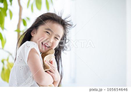 女の子のポートレート　風で飛ばされないように麦わら帽子をおさえる女の子 105654646