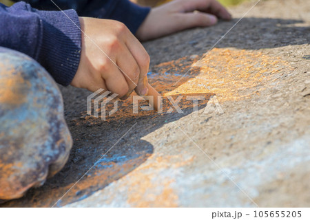 The child drawing a chalk on asphalt.  105655205