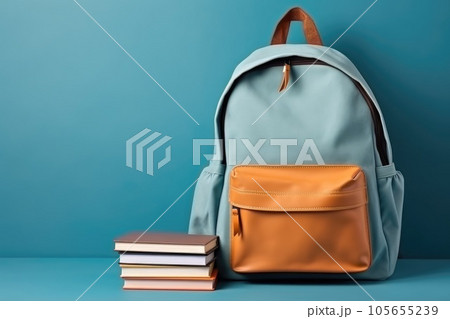 School bag and textbooks in front of a blue background. Back to school concept School bag and textbooks in front of a blue background. Back to school concept 105655239