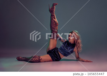 Sexy blond woman with tattoed body and long curly hair is dancing twerk in studio. 105655447