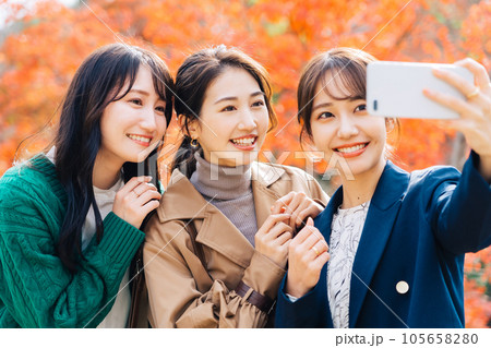 紅葉をバックに写真を撮る女性3人組 紅葉をバックに写真を撮る女性3人組 105658280
