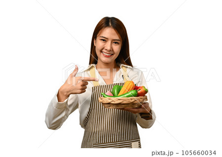 Pretty Asian woman holding basket with vegetables isolated on background. Healthy food concept.. 105660034
