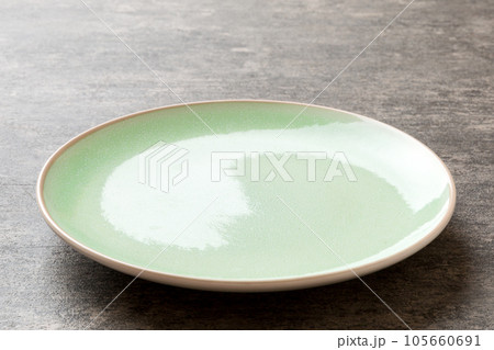 Perspective view of empty green plate on cement background. Empty space for your design Perspective view of empty green plate on cement background. Empty space for your design 105660691