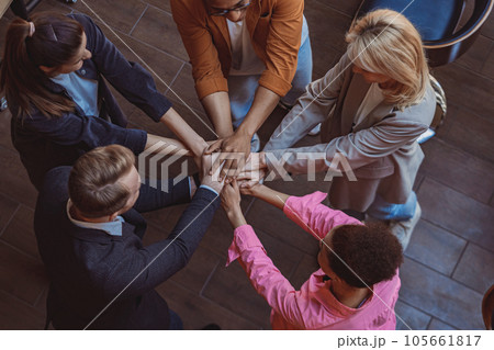 Top view of colleagues putting their arms in centre standing at office. Community concept Top view of colleagues putting their arms in centre standing at office. Community concept 105661817