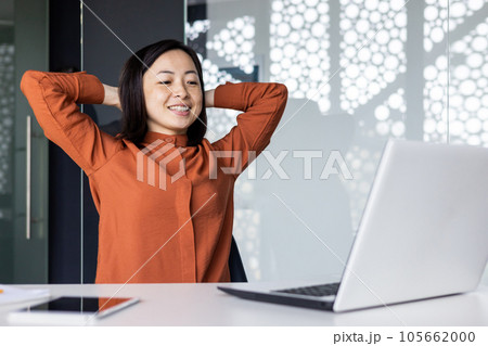 Young Asian woman resting in the office, successfully completed the work, satisfied with the results of the achievement, put her hands behind her head, dreaming, looking at the laptop screen. Young Asian woman resting in the office, successfully completed the work, satisfied with the results of the achievement, put her hands behind her head, dreaming, looking at the laptop screen. 105662000