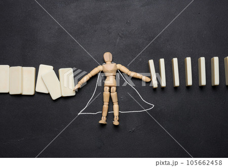 Wooden puppet toy holding a falling domino 105662458