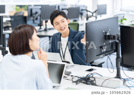 オフィスでパソコンを操作しながら会議をする男女の若いエンジニア 105662926