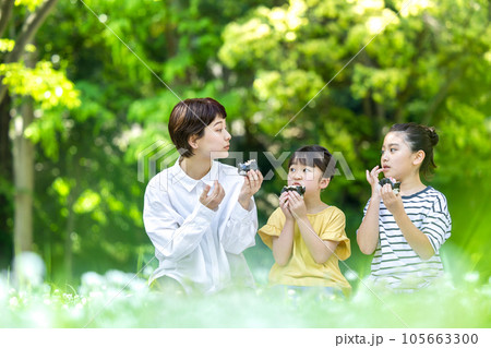 外でおにぎりを食べる大人と子供 外でおにぎりを食べる大人と子供 105663300