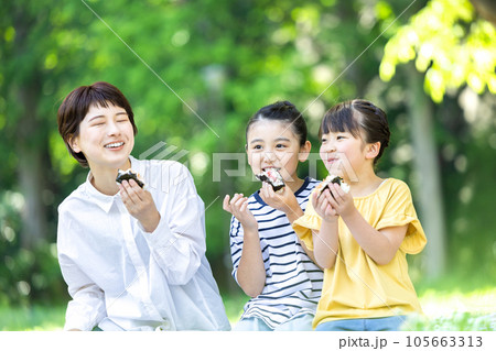 外でおにぎりを食べる大人と子供 外でおにぎりを食べる大人と子供 105663313