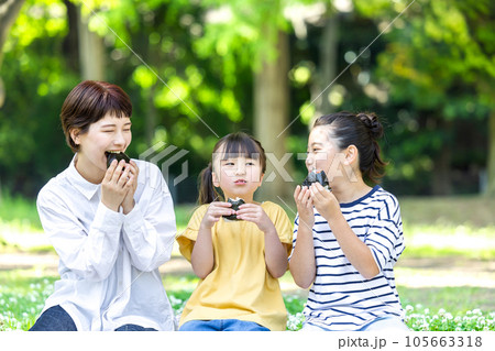 外でおにぎりを食べる大人と子供 外でおにぎりを食べる大人と子供 105663318