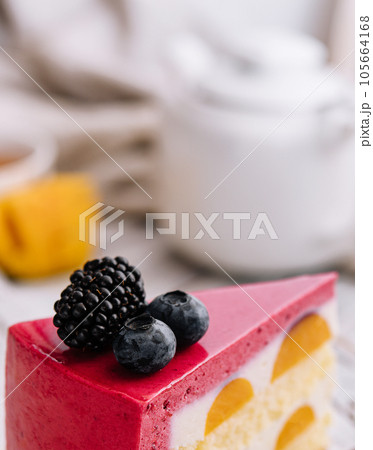A slice of a pink strawberry cheesecake served with fresh berries on a white board A slice of a pink strawberry cheesecake served with fresh berries on a white board 105664168