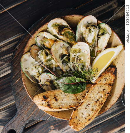 Cooked mussels in clay dish with bread and white wine glass Cooked mussels in clay dish with bread and white wine glass 105664213