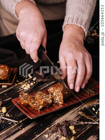 woman cuts chocolate potato dessert with a knife woman cuts chocolate potato dessert with a knife 105664353