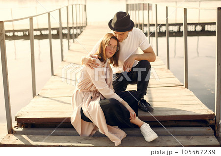 Couple by the water. Guy in a white t-shirt. Pair on a sunset background. Couple by the water. Guy in a white t-shirt. Pair on a sunset background. 105667239