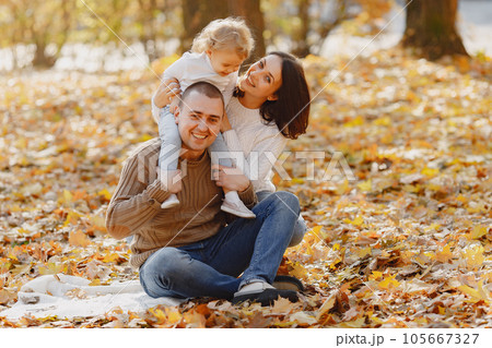 Family with cute little daughter. Father in a brown sweater. Family in a autumn field 105667327