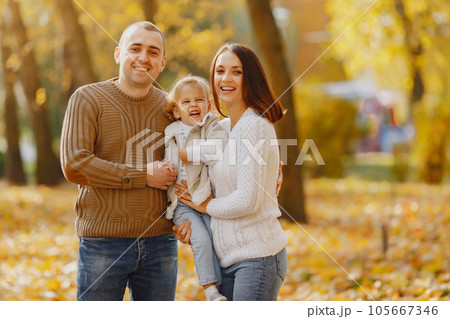 Family with cute little daughter. Father in a brown sweater. Family in a autumn field Family with cute little daughter. Father in a brown sweater. Family in a autumn field 105667346