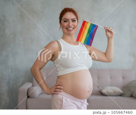 Happy pregnant woman holding a rainbow flag. Happy pregnant woman holding a rainbow flag. 105667460