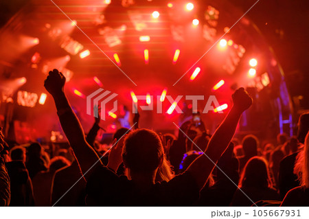 Fans with raised arms against glowing stage 105667931