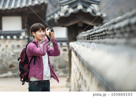 A young man holding a camera and taking pictures during a trip to Korea A young man holding a camera and taking pictures during a trip to Korea 105669103