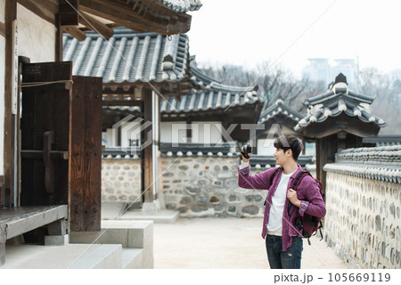 A young man holding a camera and taking pictures during a trip to Korea A young man holding a camera and taking pictures during a trip to Korea 105669119