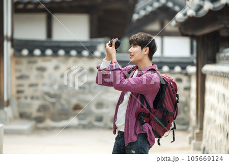 A young man holding a camera and taking pictures during a trip to Korea 105669124