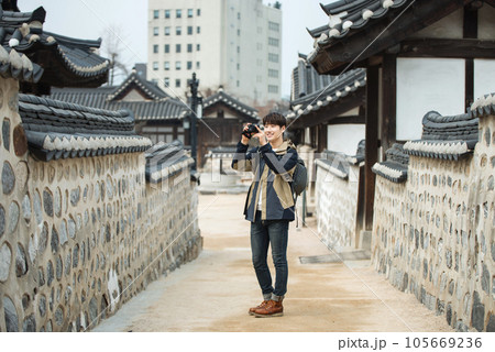 A young man holding a camera and taking pictures during a trip to Korea 105669236