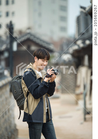 A young man holding a camera and taking pictures during a trip to Korea A young man holding a camera and taking pictures during a trip to Korea 105669267