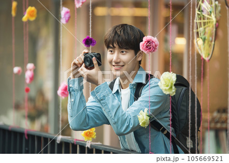A young man holding a camera and taking pictures during a trip to Korea A young man holding a camera and taking pictures during a trip to Korea 105669521