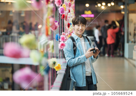A young man holding a camera and taking pictures during a trip to Korea A young man holding a camera and taking pictures during a trip to Korea 105669524