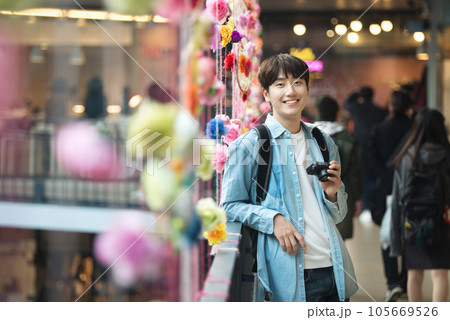 A young man holding a camera and taking pictures during a trip to Korea 105669526