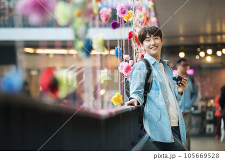 A young man holding a camera and taking pictures during a trip to Korea 105669528