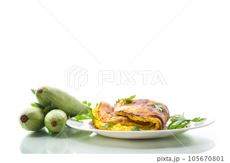 Fried omelette with zucchini,in a plate on a white background. Fried omelette with zucchini,in a plate on a white background. 105670801