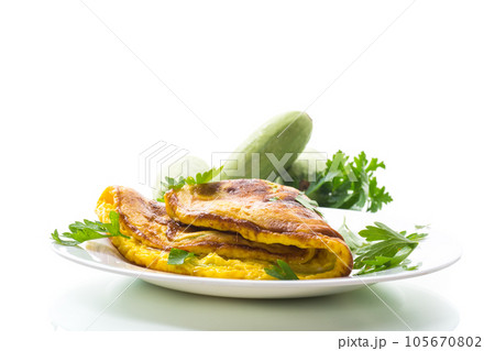 Fried omelette with zucchini,in a plate on a white background. 105670802