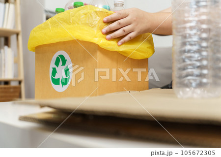 Home recycle eco green zero concept Woman throwing empty plastic bottle in recycling bin with yellow garbage bags at home. Home recycle eco green zero concept Woman throwing empty plastic bottle in recycling bin with yellow garbage bags at home. 105672305