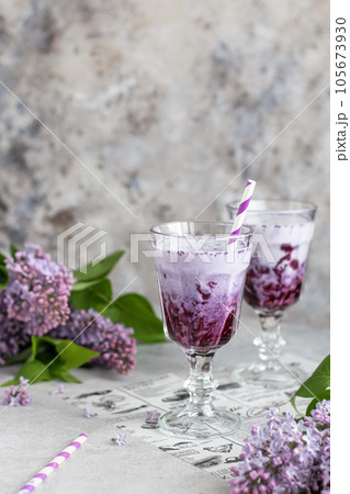 Milkshake with blueberries on gray background with lilac flowers. Vegatarian, healthy eating Milkshake with blueberries on gray background with lilac flowers. Vegatarian, healthy eating 105673930
