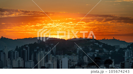 Early Dawn in the City with Silhouetted Buildings Against Orange Sky Early Dawn in the City with Silhouetted Buildings Against Orange Sky 105674243