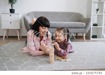 Family woman and kid building toy tower on warm floor 105675785