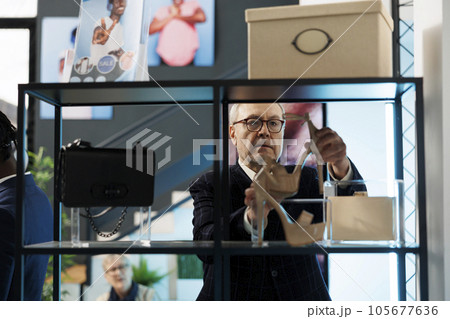 Elderly customer looking at stylish shoes in showroom, shopping for niece present in modern boutique. Caucasian man buying fashionable clothes and trendy merchandise. Fashion concept 105677636
