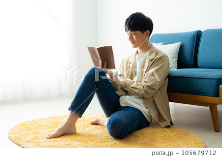 リビングで読書をする若い男性 105679712