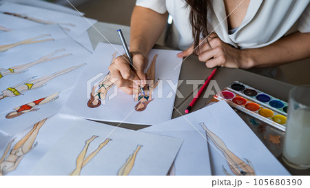 Faceless woman draws sketches of swimwear. Close-up of the hands of a fashion designer. Faceless woman draws sketches of swimwear. Close-up of the hands of a fashion designer. 105680390
