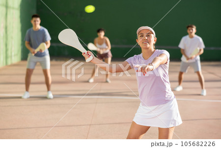 Young hispanic female pelota player swinging wooden paleta to hit ball 105682226
