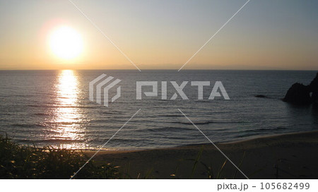 佐渡ヶ島に沈む夕日と照らされた日本海と砂浜 佐渡ヶ島に沈む夕日と照らされた日本海と砂浜 105682499