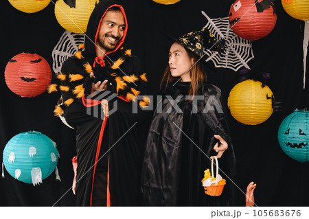 Asian young wizard Halloween man portrait and black spider on chest standing with witch woman Asian young wizard Halloween man portrait and black spider on chest standing with witch woman 105683676