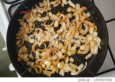Frying onion in a pan on a gas stove 105685988