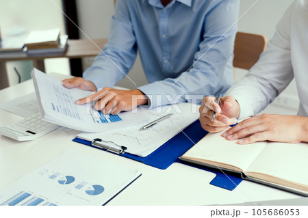 Two businessmen are analyzing company earnings figures at their desks. 105686053