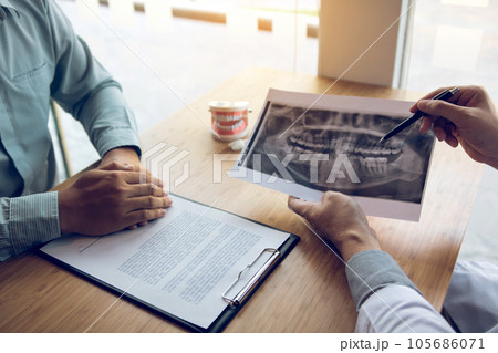 Dentist hand holding pen pointing x-ray picture and talking to the patient about medication and surgery treatment. 105686071