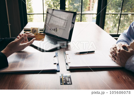 The bank clerk is talking to a customer who applied for a credit card service at the office. The bank clerk is talking to a customer who applied for a credit card service at the office. 105686078