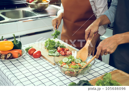 Asian couple enjoying cooking vegetable salad in the kitchen. Asian couple enjoying cooking vegetable salad in the kitchen. 105686096