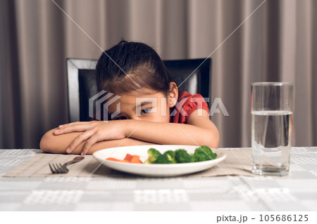 Little cute kid girl refusing to eat healthy vegetables. Children do not like to eat vegetables. Little cute kid girl refusing to eat healthy vegetables. Children do not like to eat vegetables. 105686125
